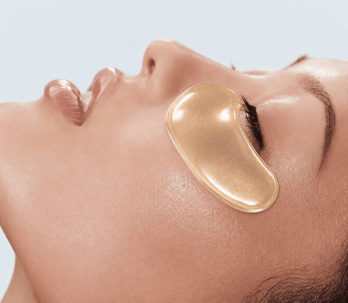 Mujer con parche de hidrogel dorado bajo el ojo